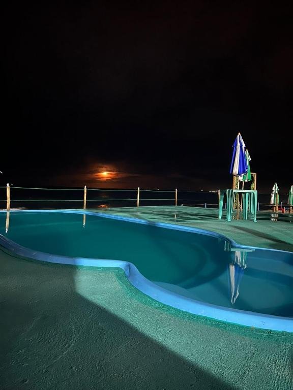 Pool at Amazônia Praia Hotel at dusk with the sea behind